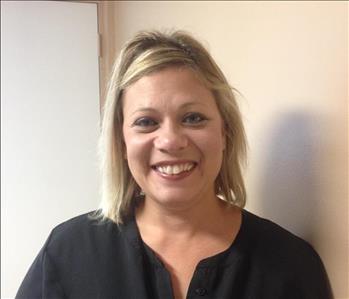Young, short blond haired smiling Caucasian female with Black v neck shirt.